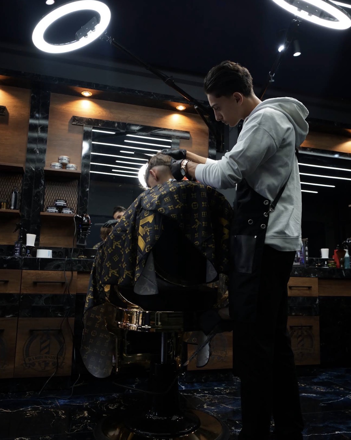 Barber knipt een klant in de gouden barberstoel bij Tiger Barbershop Heerlen